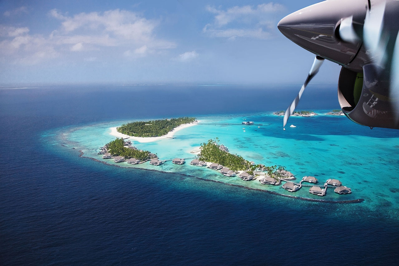 Foto aus dem Wasserflugzeug auf die fünf Inseln des Luxushotels Cheval Blanc Randheli mit türkisfarbenen Atollen des indischen Ozeans der Malediven