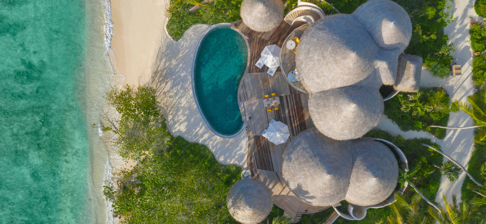 Blick aus der Vogelperspektive auf die Villa mit privatem Pool am Strand vom The Nautilus Malediven Luxusresort am schneeweißen Strand des indischen Ozeans