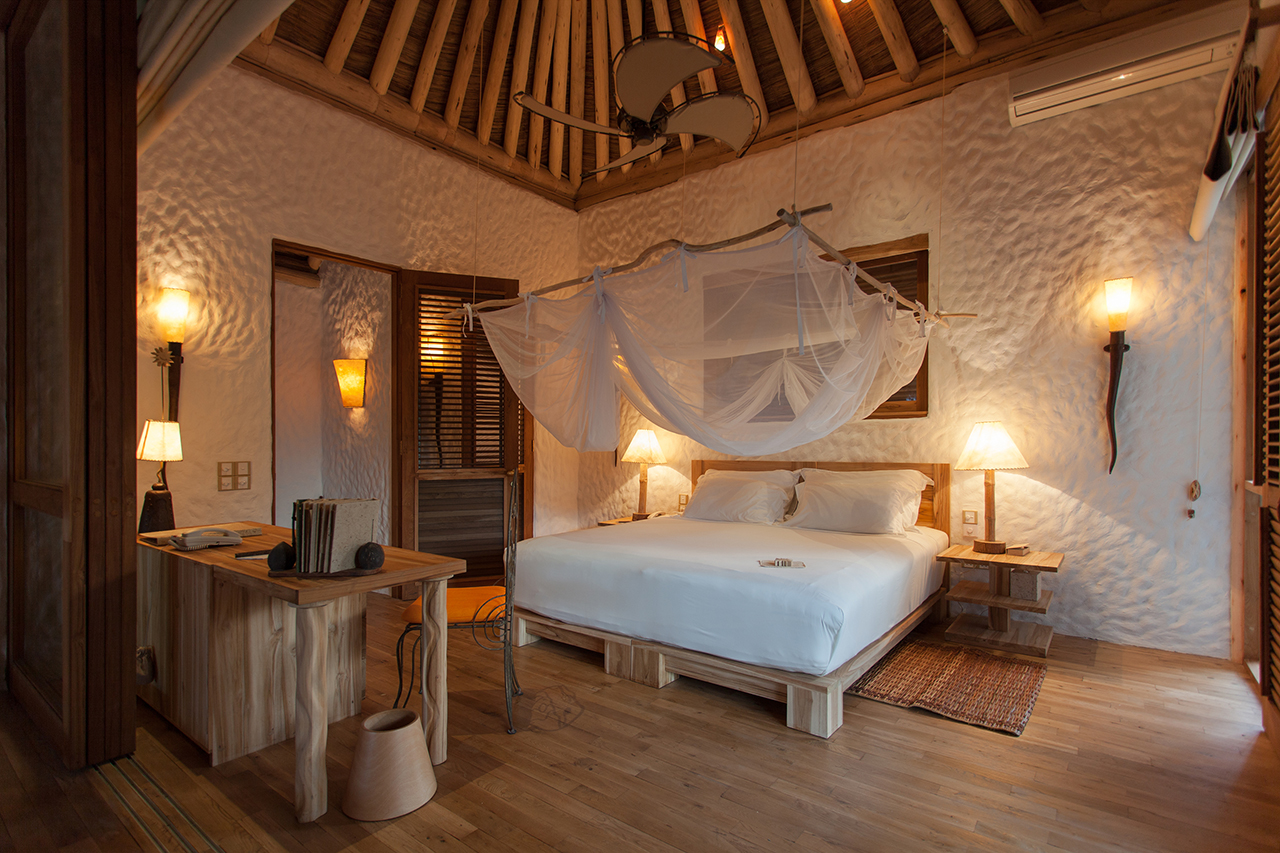 Schlafzimmer mit viel Holz und Moskitonetz im Soneva Fushi Luxus Eco Resort der Malediven