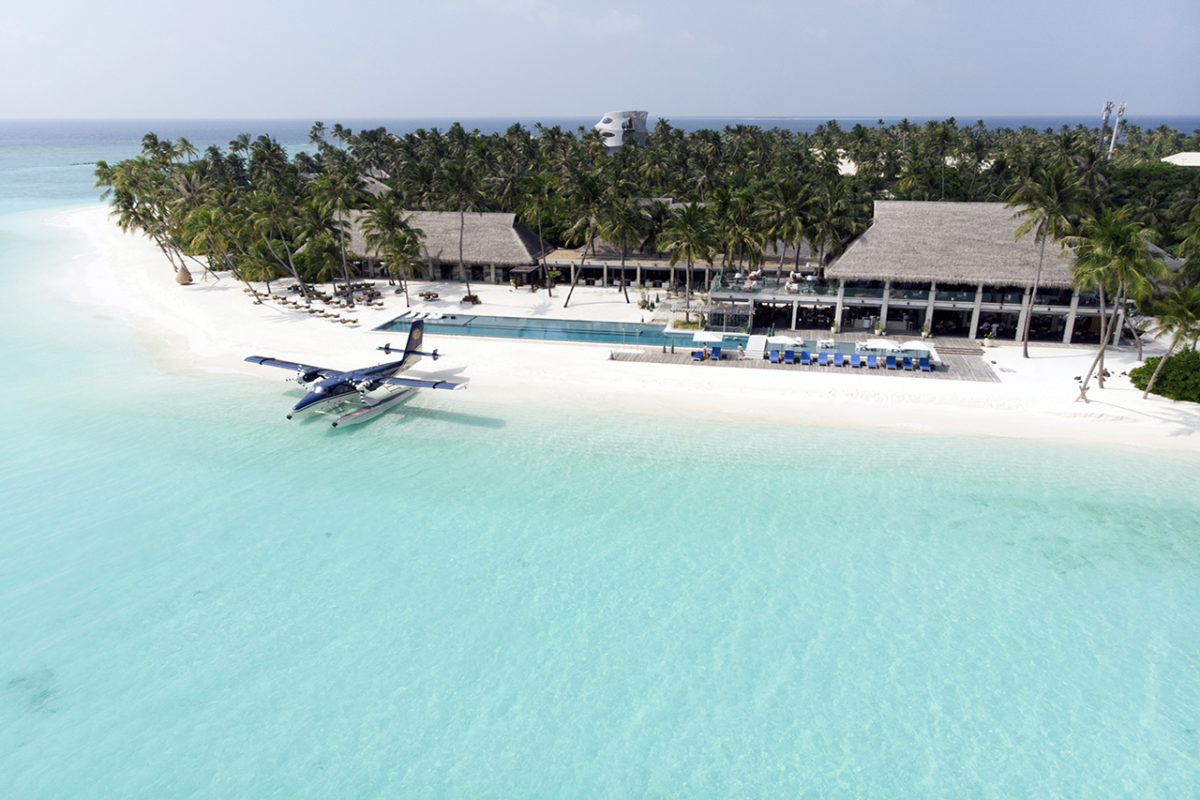 Blick aus der Vogelperspektive auf den schneeweißen Sandstrand des Luxusresorts Velaa Private Island mit dem privaten Wasserflugzeug des Resorts in der türkisfarbenen Lagune stehend