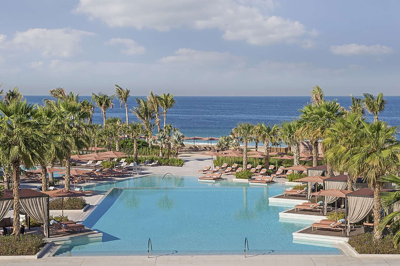 Hauptpool mit Palmen und unverbautem Meerblick des Caesars Palace Bluewater Hotel in Dubai