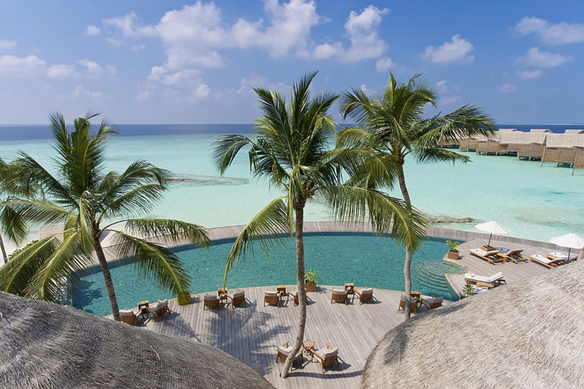 Hauptpool der Luxusinsel Milaidhoo auf den Malediven mit Blick auf das türkisfarbene Wasser des indischen Ozeans